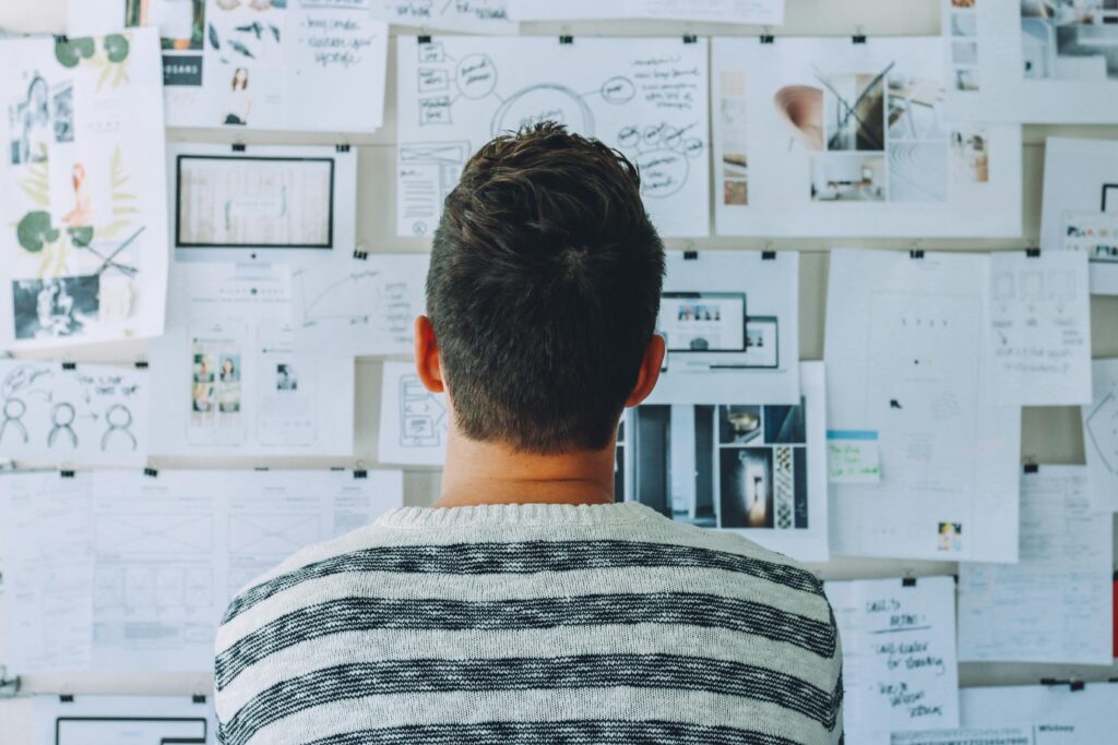 A man looking at a board with strategy documents pinned to it